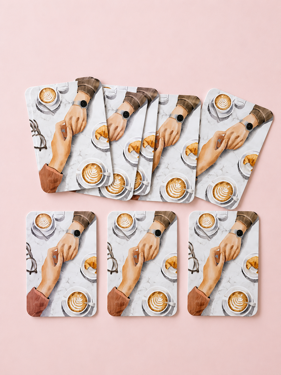 Mini cards featuring an illustrated café scene with two hands touching over coffee and croissants, arranged on a soft powder pink background.