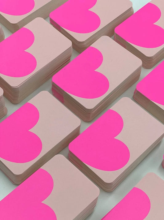 "Stacks of cream card stock, each featuring a large pink heart shape cropped at the top edge, shown in bulk wholesale product photography.