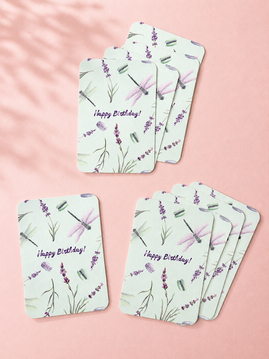 Mint green Happy Birthday cards with watercolor lavender, dragonflies and macarons, arranged on a soft powder pink background