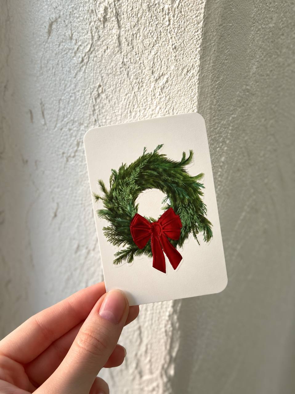 Hand-held lifestyle photo of the existing Christmas Wreath: Scarlet Bow mini card — adding it to that file.
