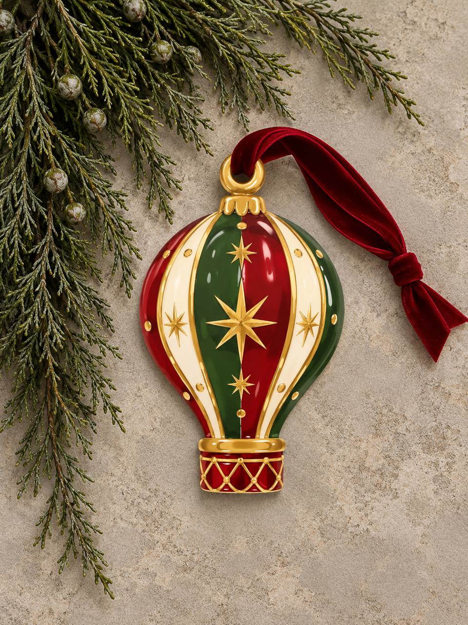 Shaped paper ornament "Circus Hot Air Balloon" in red, green, cream, and gold with a star pattern, hung with a red ribbon among pine branches.
