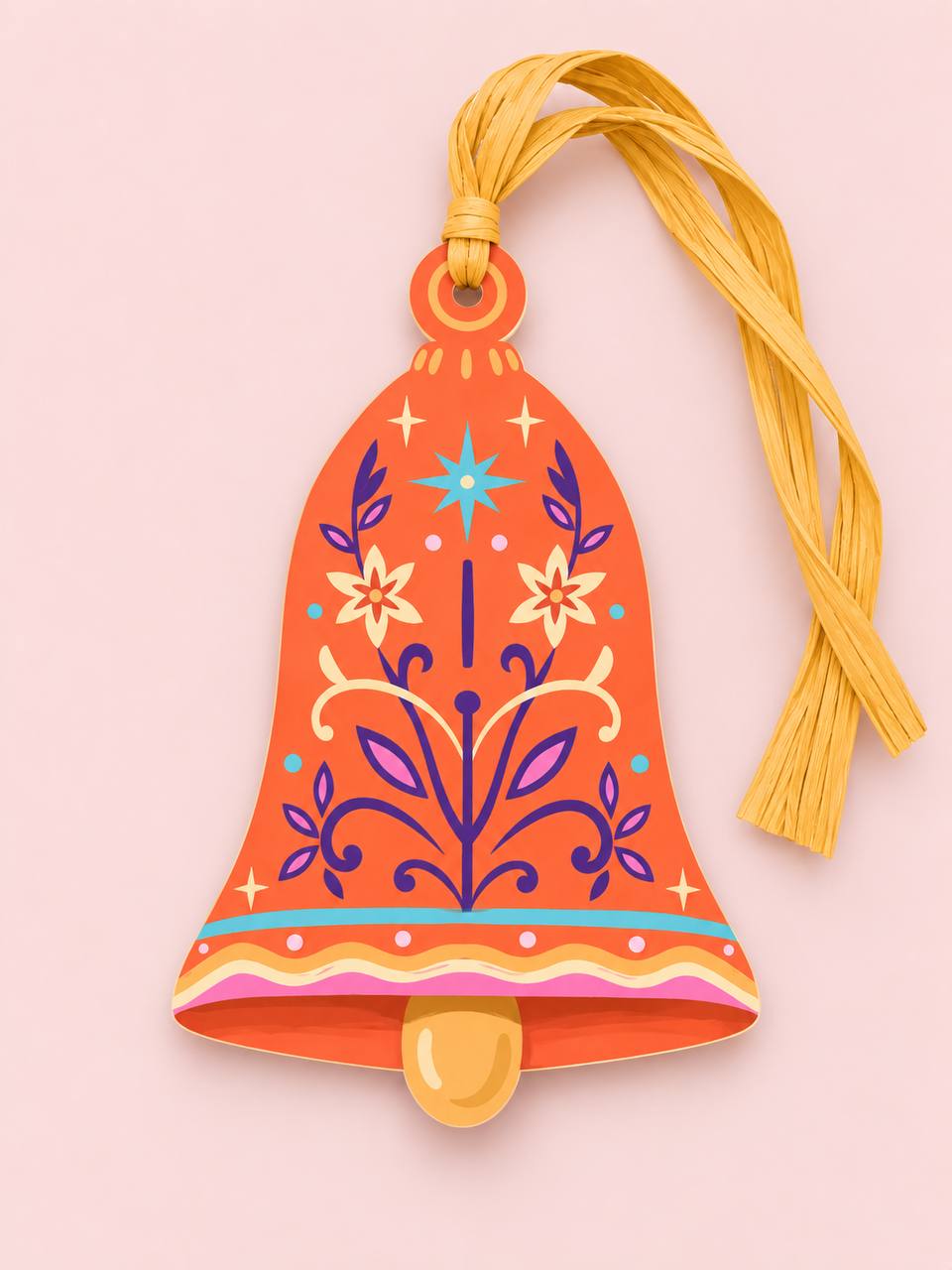 Shaped paper ornament "Talisman Bell" in orange with a purple and yellow floral folk-art design, tied with a yellow raffia tassel on a pink background.