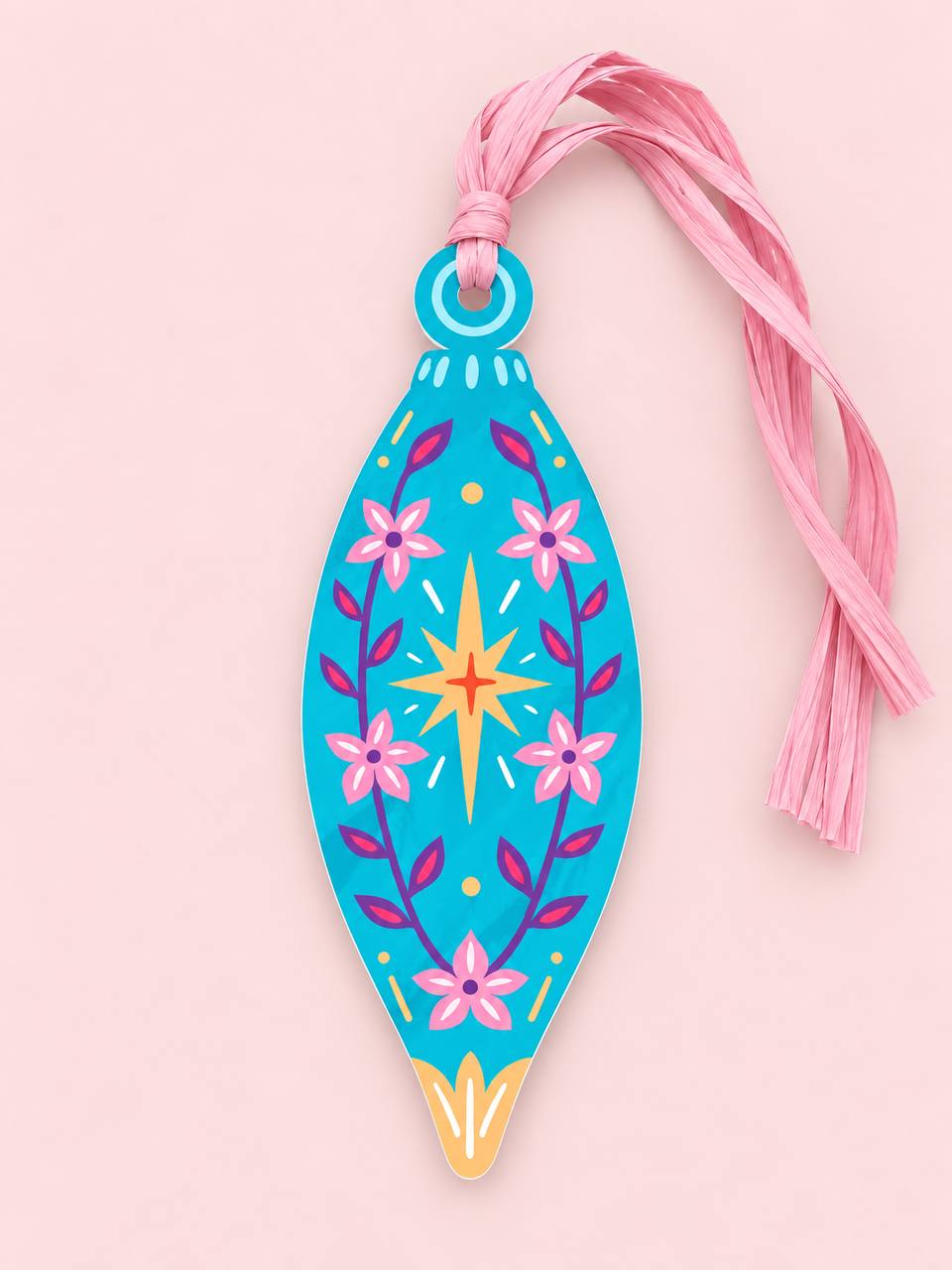 Shaped paper ornament "Talisman Finial" in turquoise with a pink floral and starburst folk-art design, tied with a pink raffia tassel on a pink background.